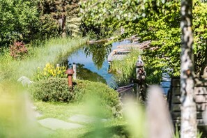 A garden with a pond, stone pathway, and a rustic building in the background. - Residence Lusina (Luson)