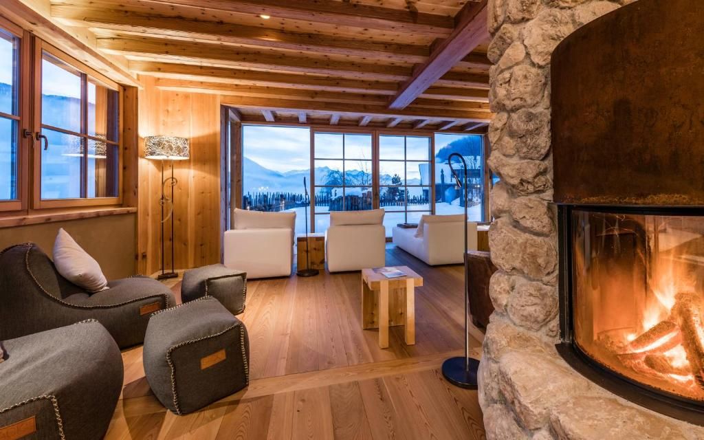 Un interior acogedor con chimenea de piedra, vigas de madera en el techo y un amplio ventanal con vistas a un paisaje nevado.