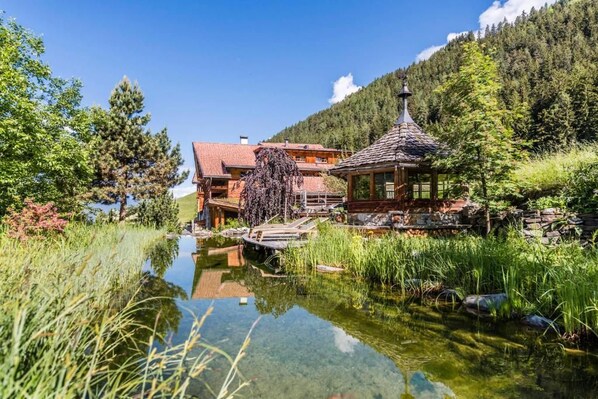 Eine Lodge mit Teich, Holzterrasse und Bergblick.