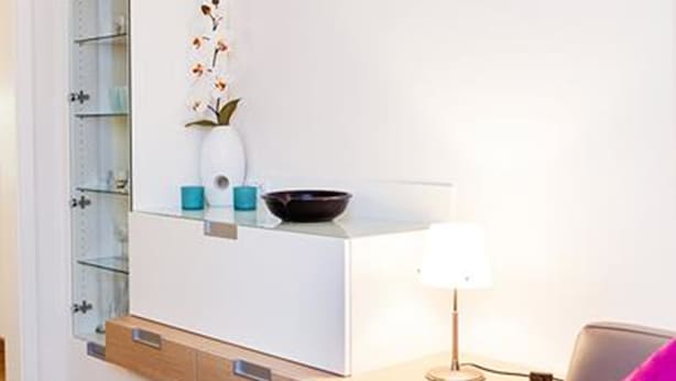 A modern bathroom with a white vanity, a glass shelf, a vase with flowers, and a wall-mounted mirror. - Ferienwohnung Sturm (Reit im Winkl)