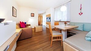 A compact living space with a kitchenette, a dining area, and a seating area. - Ferienwohnung Sturm (Reit im Winkl)