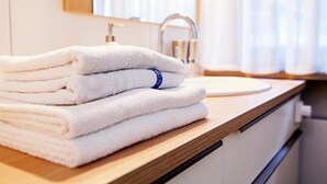 A stack of white towels on a wooden countertop in a bathroom. - Ferienwohnung Sturm (Reit im Winkl)