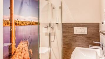 A modern bathroom with a glass shower enclosure, a wooden vanity, and a large mirror.