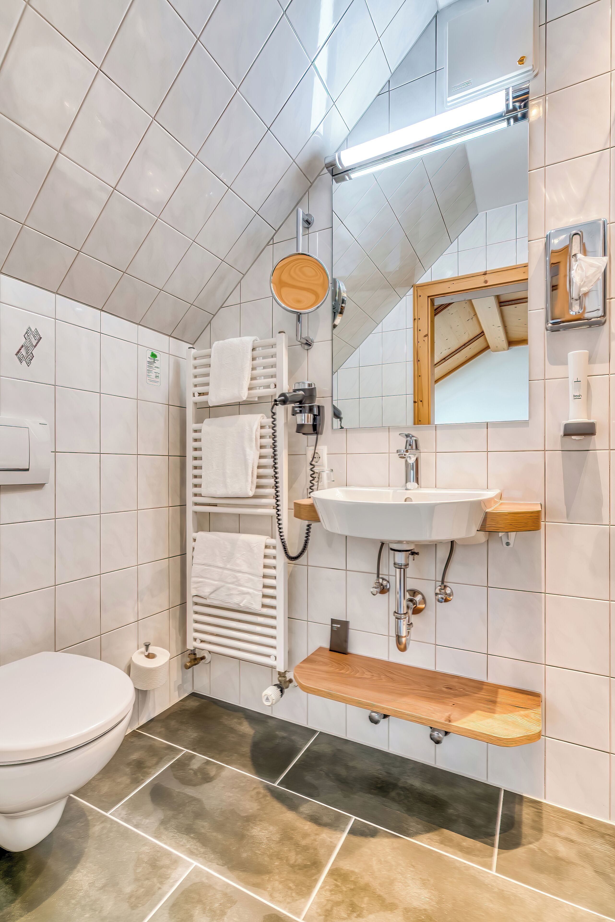 Ein modernes Badezimmer mit Toilette, Waschbecken, Spiegel und Handtuchhalter.