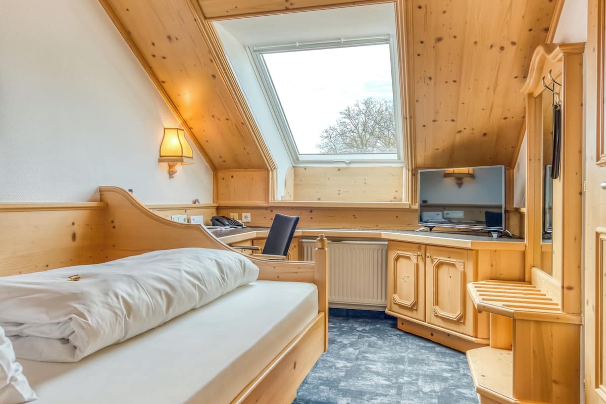 A cozy room with a bed, a desk, a chair, and a television.