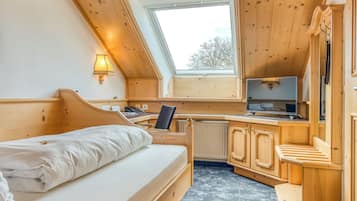 Ein gemütliches Zimmer mit einem Bett, einem Schreibtisch, einem Sessel und einem Fernseher.