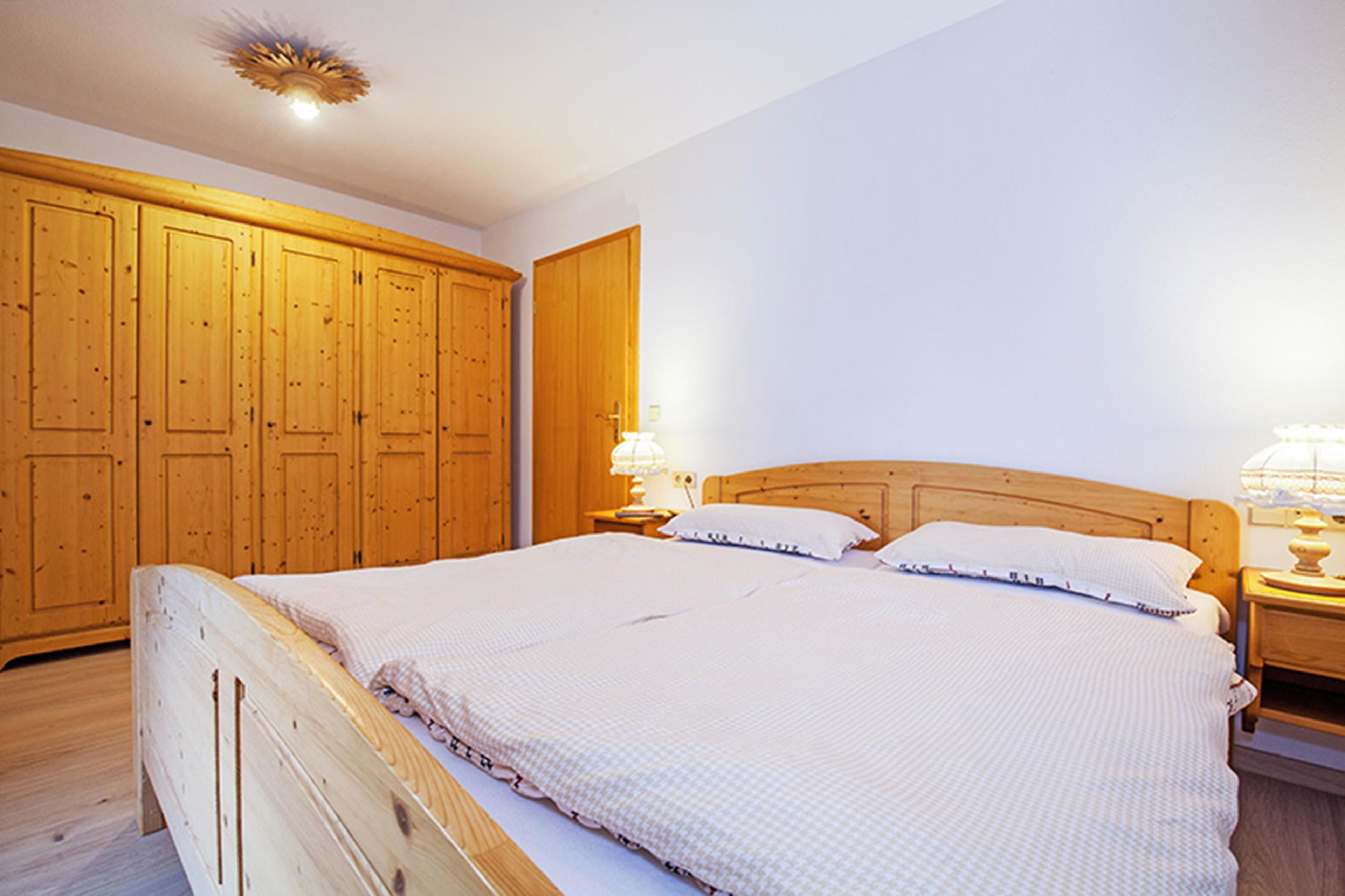 Una camera da letto con un letto grande, un'armadiatura in legno e lampade da comodino.