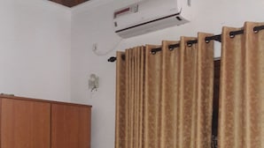 A bedroom with a bed, brown curtains, a wardrobe, and an air conditioning unit. - Roo Neeroga (Marawila)