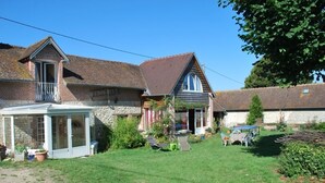 A two-story house with a covered patio, a small garden, and a car parked in the driveway. - Au Vieux Tilleul B&B (Les Trois Lacs)