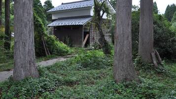 A traditional Japanese house surrounded by dense greenery and trees.