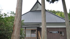 Ein Gebäude mit einem Ziegeldach, einer Holztür und einem Schild mit der Aufschrift 'AOIE'.
