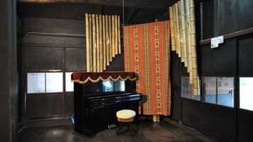 A room with a piano, a stool, and a curtain with a pattern.