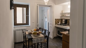 Cocina compacta con comedor, radiador, ventana y candelabro.