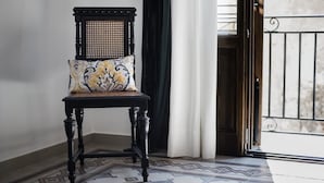 Una silla con un cojín estampado en una habitación con baldosas de suelo estampadas y una puerta con reja de metal.