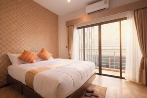A hotel room with a large bed, a view of the city through a sliding glass door, and an air conditioning unit on the wall.