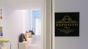 Zona de recepción de hotel con un cartel que dice 'ESPOSITO Plaza Rooms & Suites'.
