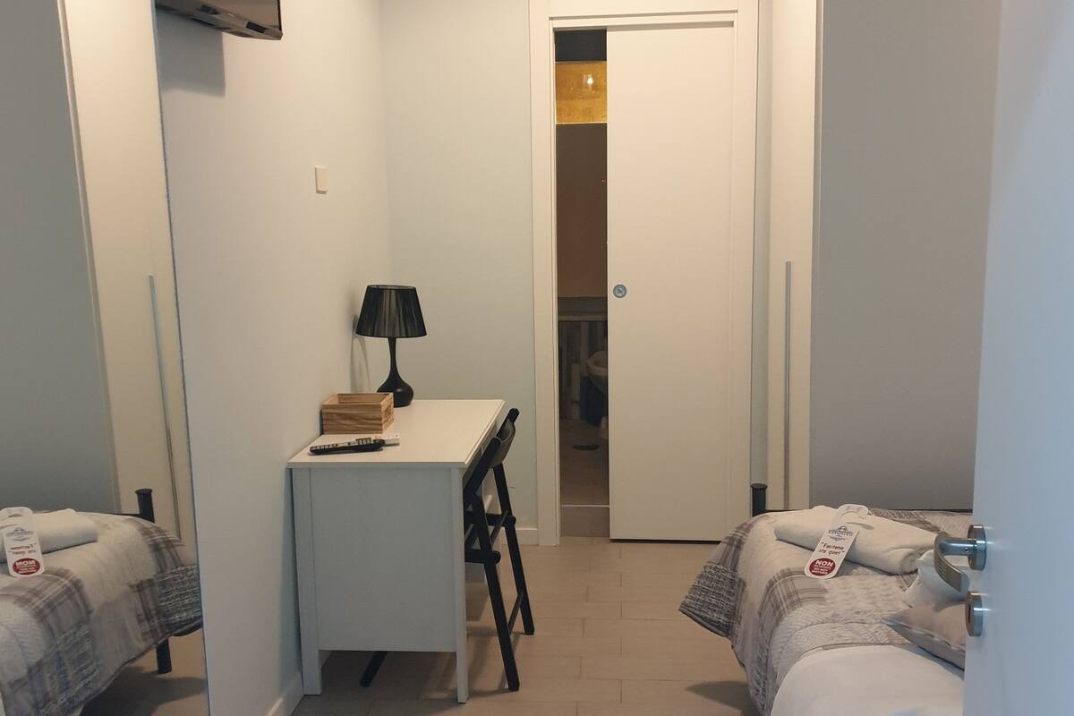 Een slaapkamer met twee bedden, een bureau, een stoel, een lamp en een kledingkast.