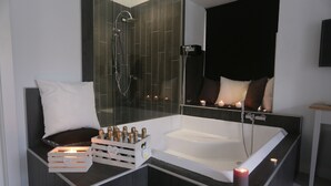 Un baño moderno con una bañera grande, una ducha con mampara de vidrio y un tocador con espejo.