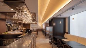 A modern restaurant with a long counter, multiple seating areas, and a decorative chandelier. - Ginza Capital Hotel Moegi (Tokyo)