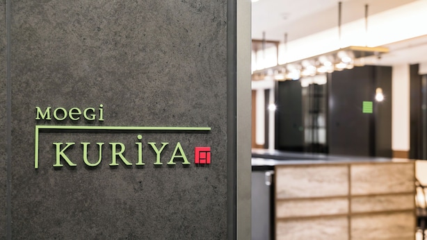 A reception desk with a modern design, featuring a logo with the name 'Moegi Kuriya' and a red square symbol. - Ginza Capital Hotel Moegi (Tokyo)