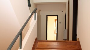 Una escalera de madera con barandilla de metal que lleva a una puerta en la parte superior.