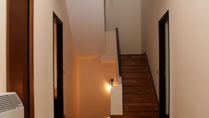 Un pasillo con suelo de madera, una escalera y un radiador.