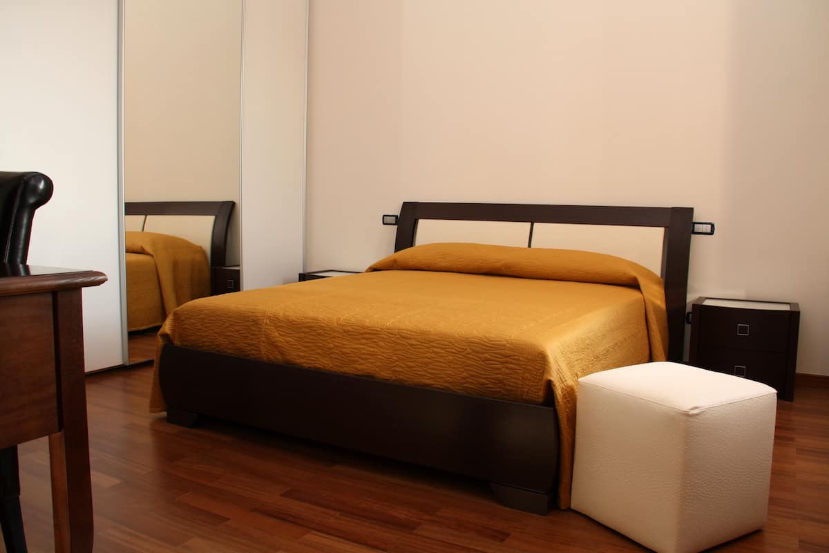 A neatly arranged bedroom with a bed, a bedside table, and a small cabinet.