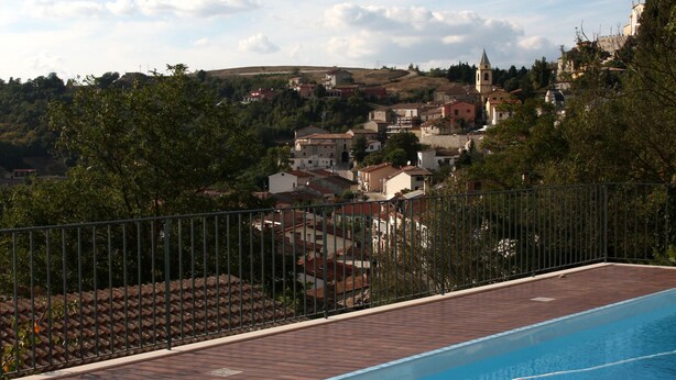 Una piscina con vistas a un pueblo y una iglesia al fondo.