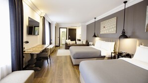 Ein Hotelzimmer mit zwei Betten, einem Esstisch, einer Couch und einem Fernseher.