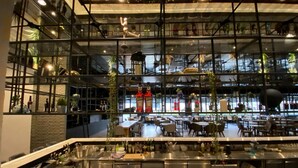 Ein modernes Restaurant mit hoher Decke, freiliegenden Lüftungsrohren und unterschiedlichen Sitzgelegenheiten.