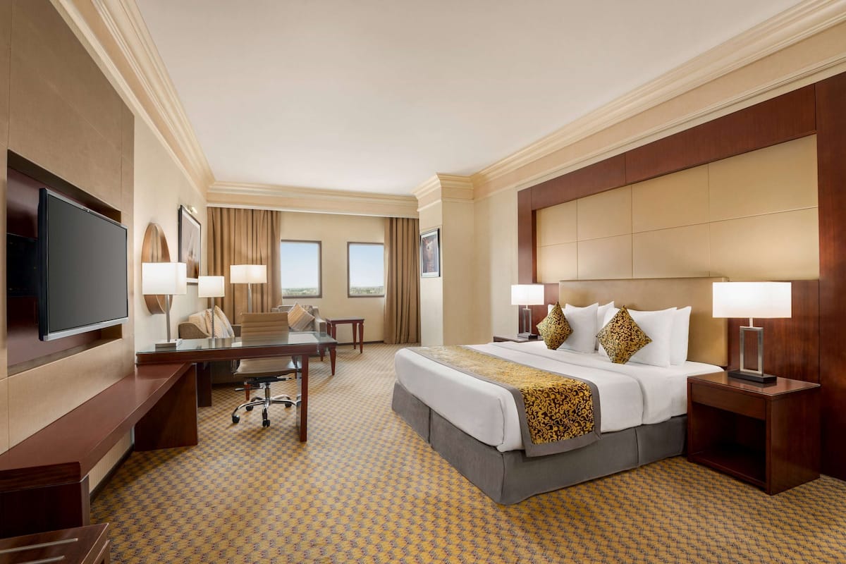 A hotel room with a large bed, a desk, a television, and a view of the outdoors.