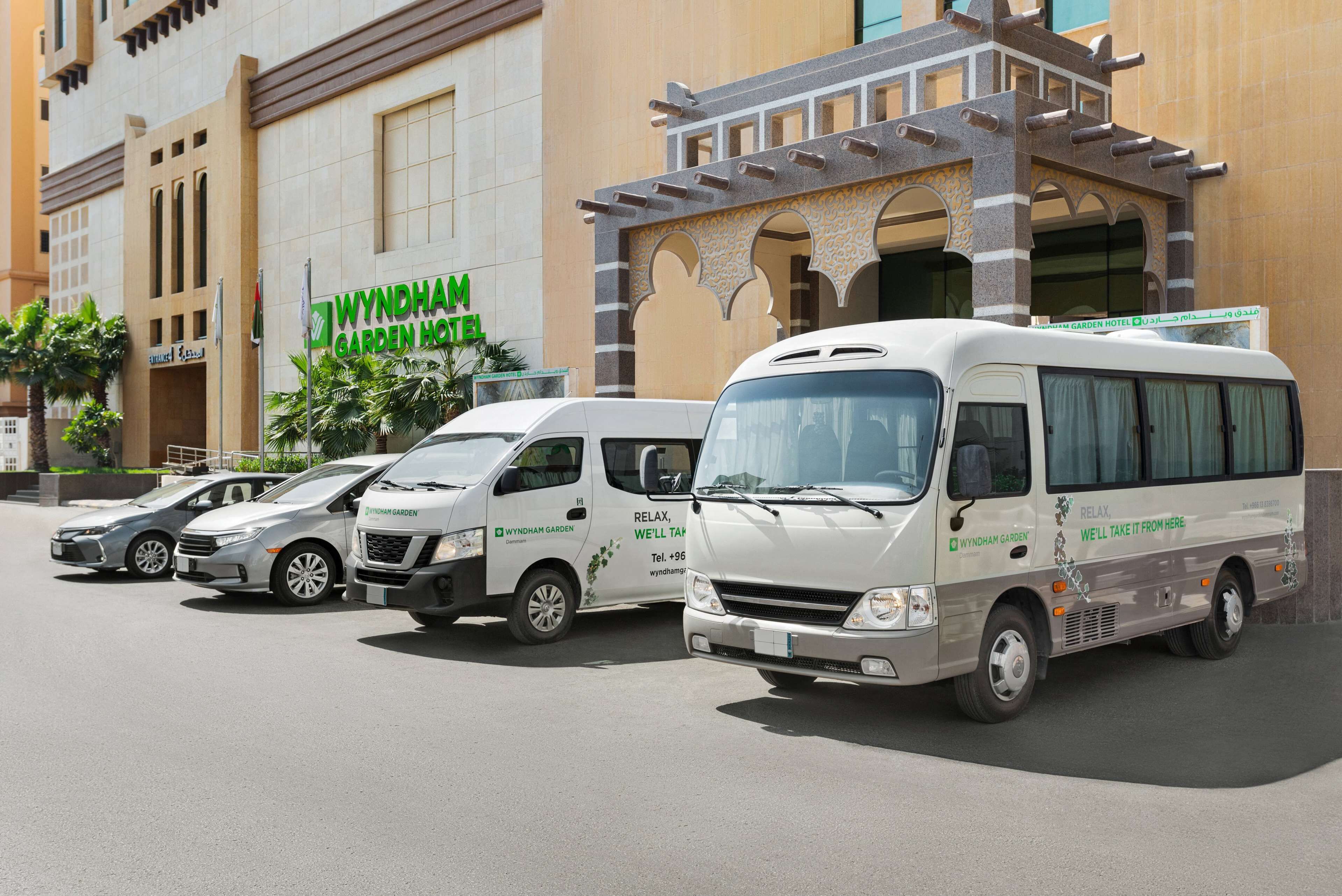 Una fila de minibuses de Wyndham Garden Hotel estacionados frente al hotel.