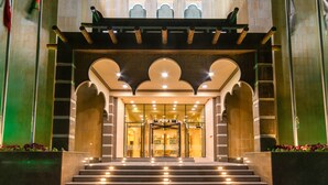 L’entrée d’un hôtel, avec un grand escalier, une porte tournante et un arc décoratif.