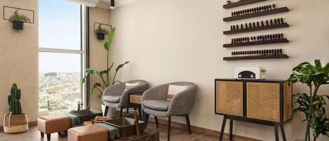 Una sala de estar moderna con un ventanal grande, dos sillones grises, una mesa de centro de madera, una mesita auxiliar de ratán y un estante de pared con varios objetos.