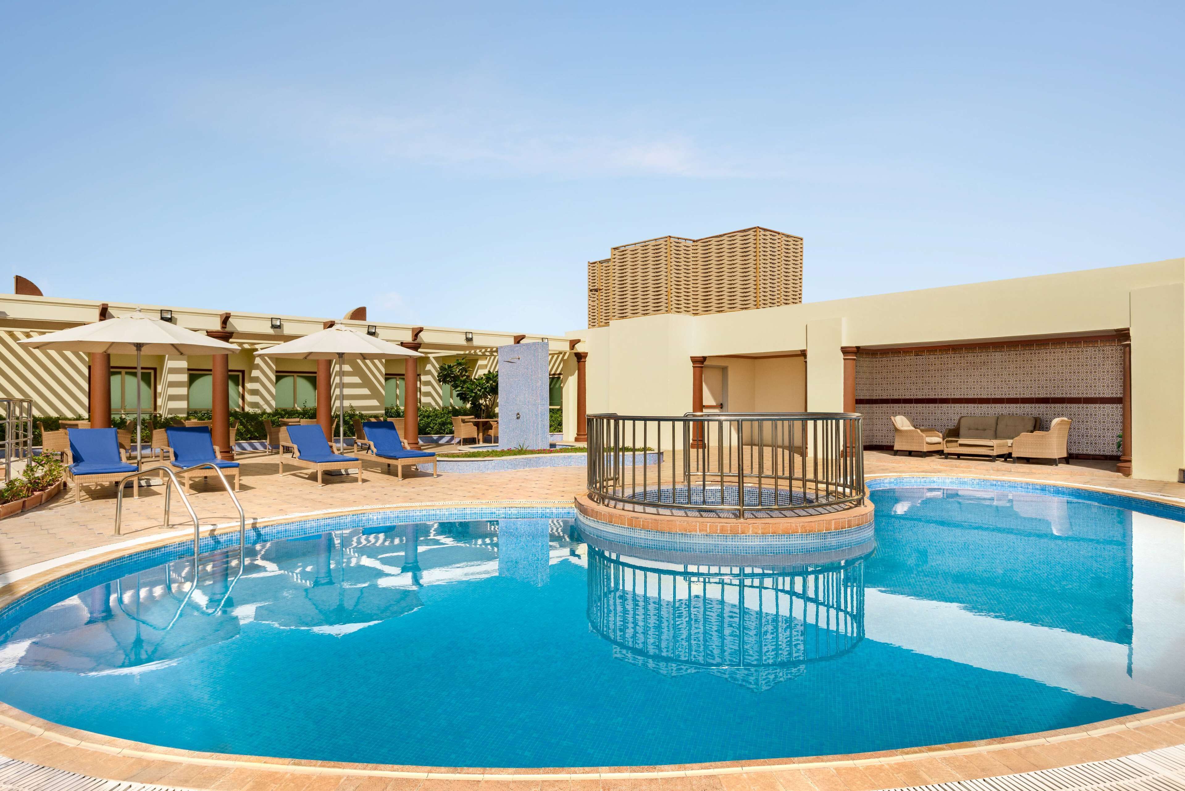 A swimming pool with a circular deck, blue lounge chairs, and umbrellas.