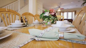 Une table à manger dressée avec des assiettes, des tasses et un centre de table composé de fleurs.