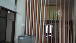 Een kamer met een scheidingswand, een klein tafeltje met een apparaat, en een deur naar een andere kamer.