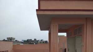 Een dak met een roze gebouw, een waterreservoir en een betonnen vloer.