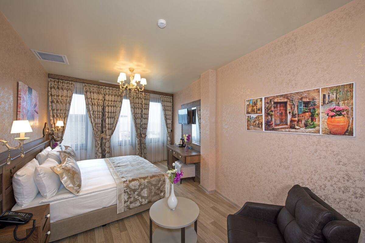 A hotel room with a bed, bedside table, lamp, and a painting on the wall.