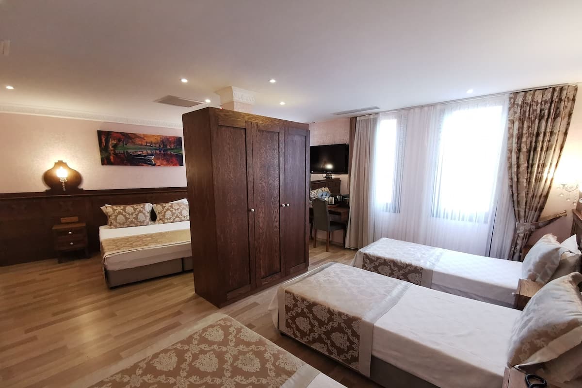 A hotel room with two beds, a desk, a TV, and a painting on the wall.