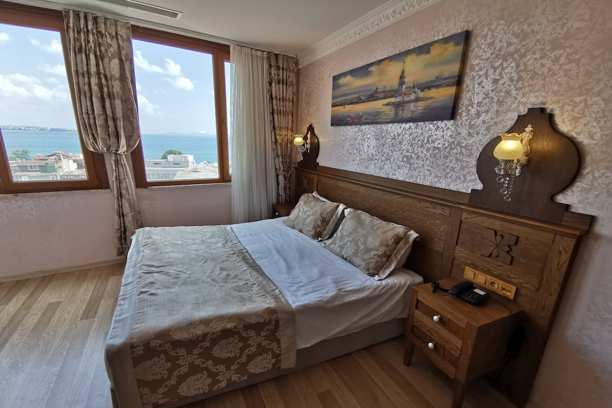 A bedroom with a bed, wooden nightstand, and a painting on the wall.