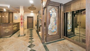 A lobby with a check-in counter, a reception desk, and a decorative wall with a sculpture. - Perapolis Hotel (Istanbul)