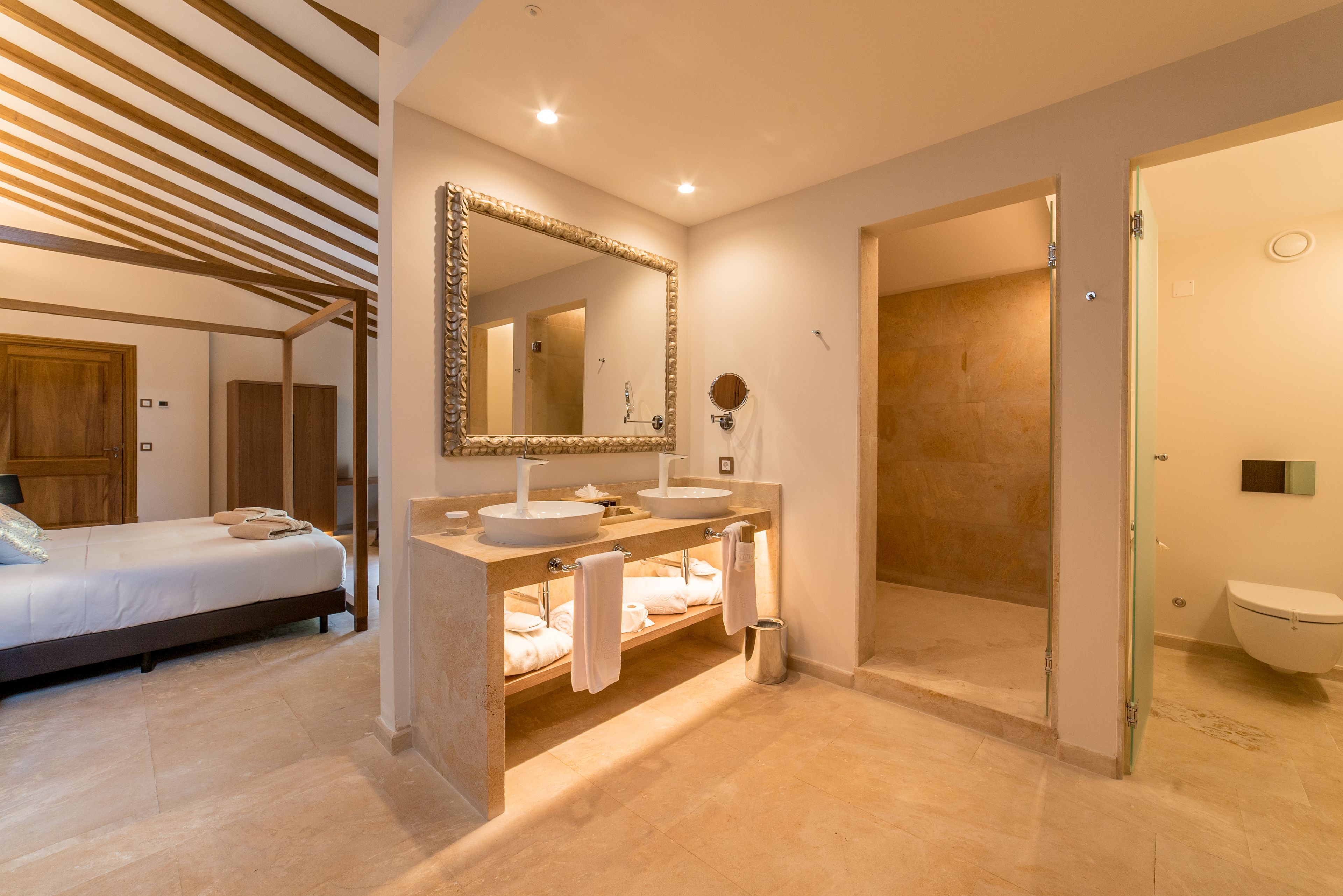 Un baño moderno con un espejo grande, dos lavamanos, ducha y retrete.