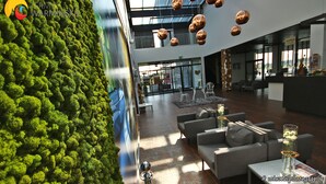 Un vestíbulo moderno con una pared verde, zona de estar y lámparas esféricas colgantes.