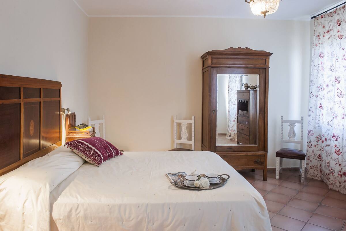 Ein Schlafzimmer mit einem Bett, einem Holzschrank, einem Spiegel und einer Ablage mit Teeutensilien.