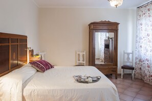 A bedroom with a bed, a wooden wardrobe, a mirror, and a tray with tea items. - Villa Marchetti (Cupra Marittima)