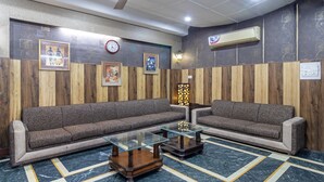 A room with two sofas, a glass coffee table, a wall clock, and an air conditioning unit. - Itsy Hotels Paradise Inn, Haridwar (Haridwar)