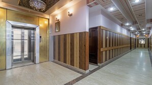 A modern elevator with a digital display, a hallway with wooden paneling, and a marble floor. - Itsy Hotels Paradise Inn, Haridwar (Haridwar)