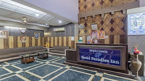 A reception area with a 'Welcome Hotel Paradise Inn' sign, a reception desk, a seating area with sofas, a clock, and a patterned wall. - Itsy Hotels Paradise Inn, Haridwar (Haridwar)