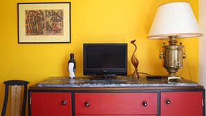 A room with a red cabinet, a black Sony TV, a brass lamp, and a framed artwork on the wall. - Chambre d'Hôtes Txori Etxea (Arcangues)